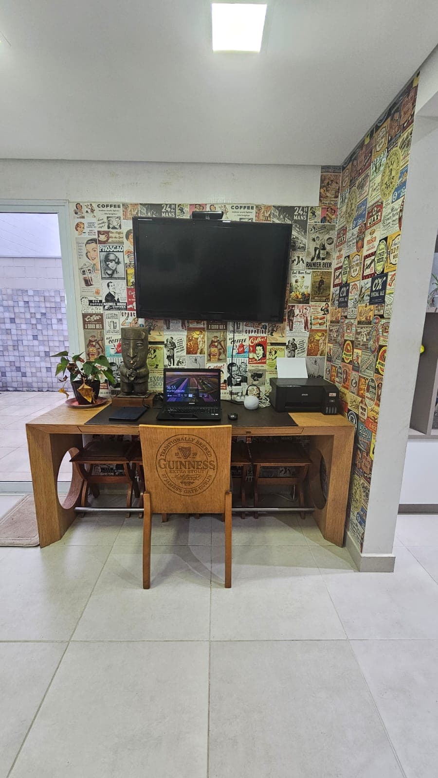 Espaço de escritório em casa com mesa de madeira, TV e parede decorada